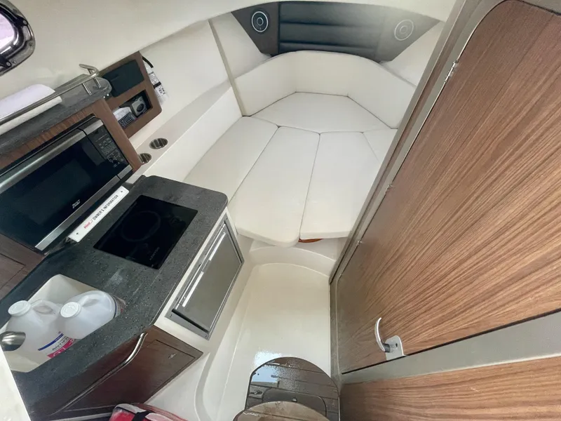 Slide: The Image of 2022 Boston Whaler 285 Conquest cabin interior with kitchenette and seating area. - 17