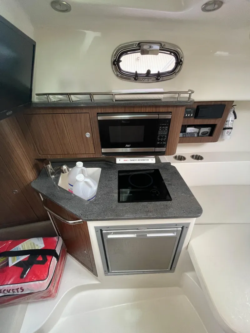 Slide: The Image of 2022 Boston Whaler 285 Conquest interior kitchen with stove, microwave, and storage cabinets. - 18