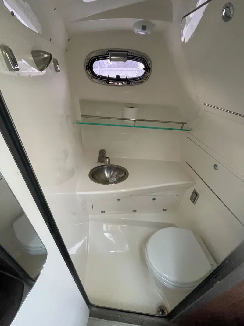 Slide: The Image of 2022 Boston Whaler 285 Conquest boat bathroom with sink, toilet, and porthole window. - 20