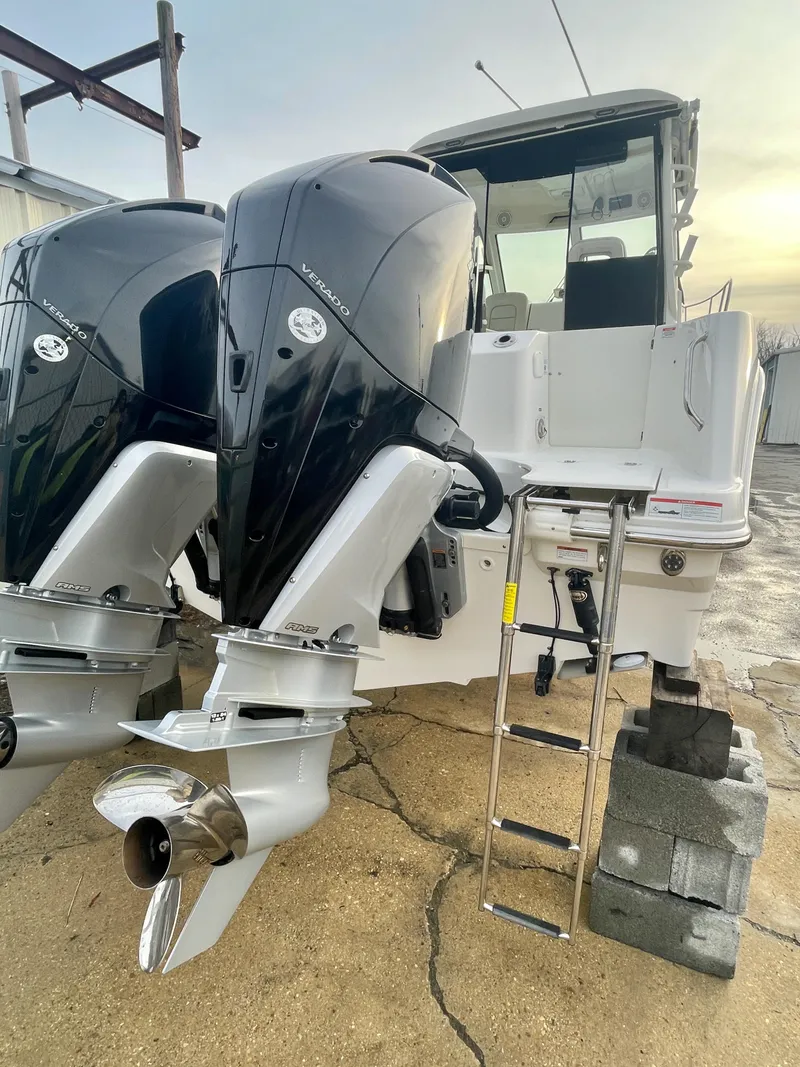 Slide: The Image of 2022 Boston Whaler 285 Conquest with dual outboard engines and ladder, docked on land. - 5