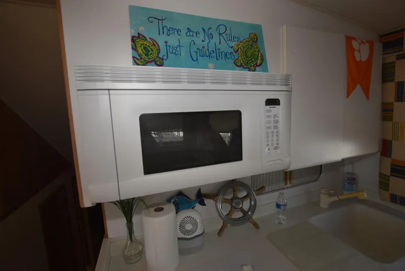 Slide: The Image of Interior of 1996 Hatteras 50 Convertible with TV, nautical decor, and striped curtains. - 21