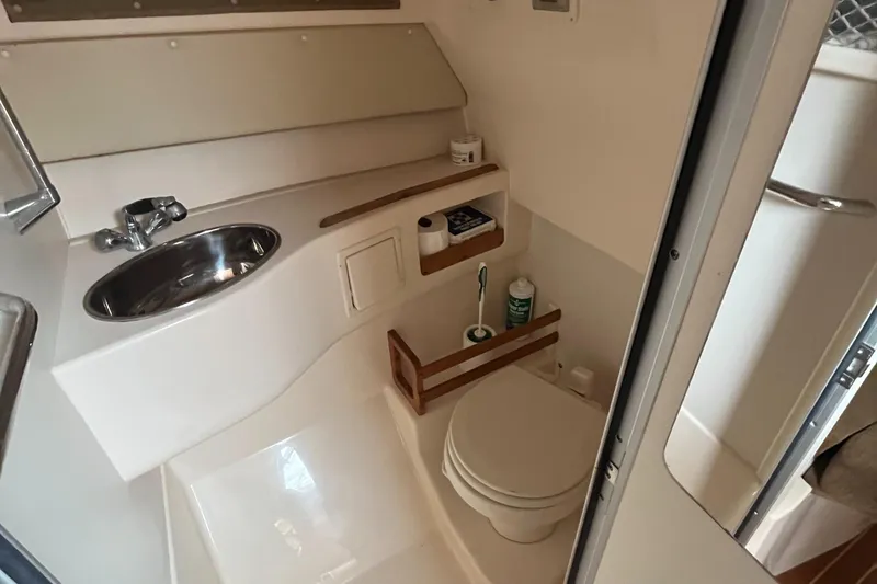 Slide: The Image of 2012 Grady-White Express 305 boat bathroom with sink, toilet, and storage shelves. - 17