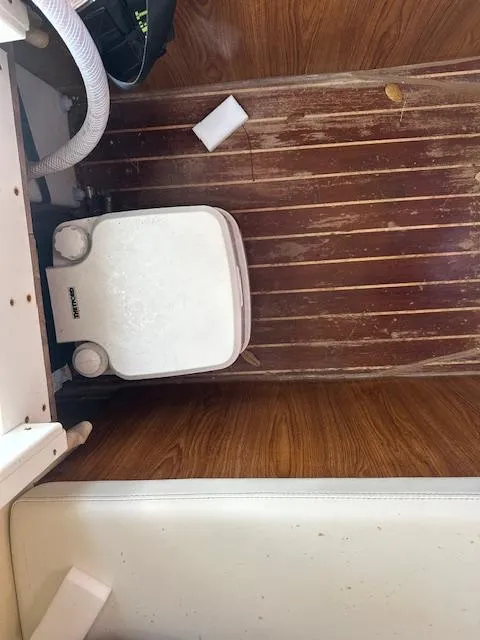 Slide: The Image of 2011 Custom Carolina 26 boat interior with wooden flooring and portable toilet. - 10