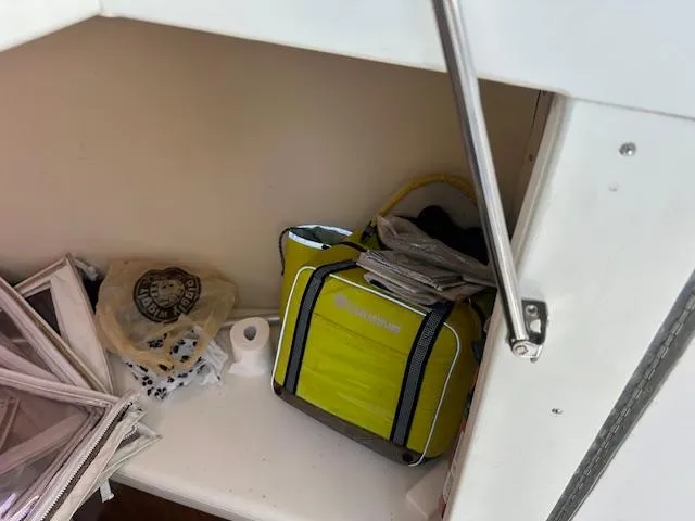 Slide: The Image of Storage compartment with a yellow bag, paper towels, and miscellaneous items on a Custom Carolina 26 boat. - 11
