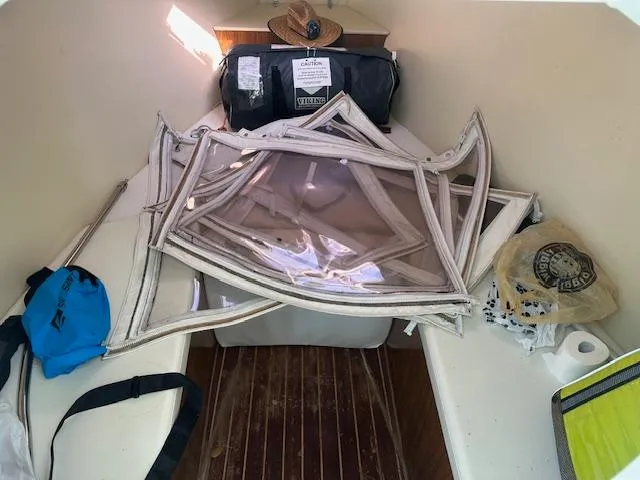 Slide: The Image of Interior of 2011 Custom Carolina 26 boat with gear and supplies on wooden floor. - 13