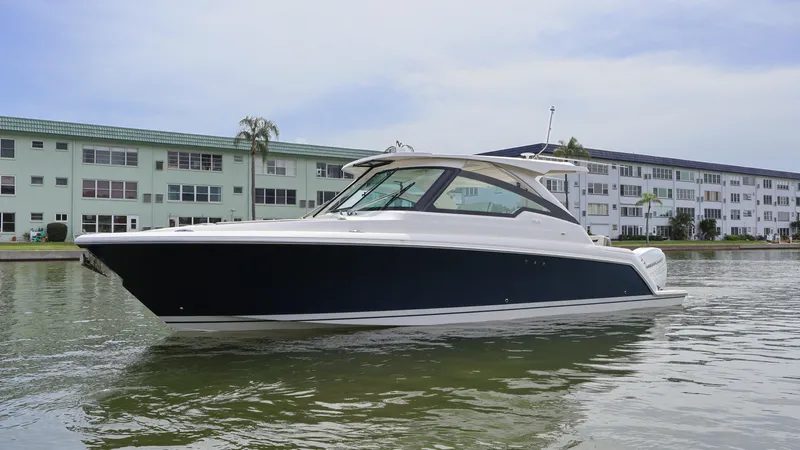 Slide: The Image of 2022 Tiara Yachts 34 LX cruising on calm waters near residential buildings. - 1