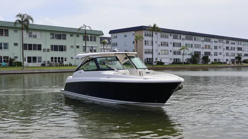 Slide: The Image of 2022 Tiara Yachts 34 LX cruising near waterfront buildings. - 2