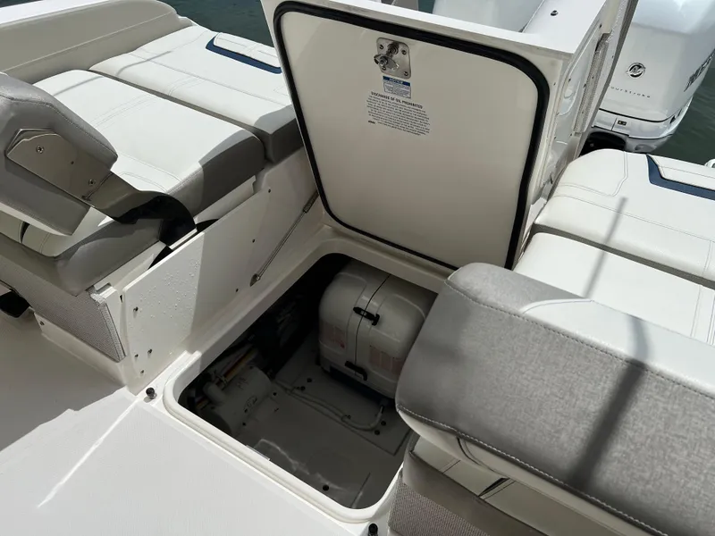 Slide: The Image of 2022 Tiara Yachts 34 LX interior storage compartment with open hatch, showcasing seating and engine access. - 22