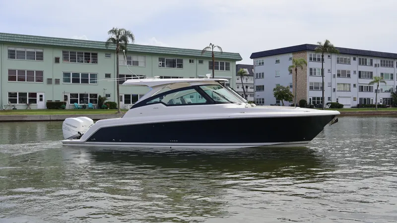 Slide: The Image of 2022 Tiara Yachts 34 LX cruising on a calm waterway near residential buildings. - 4