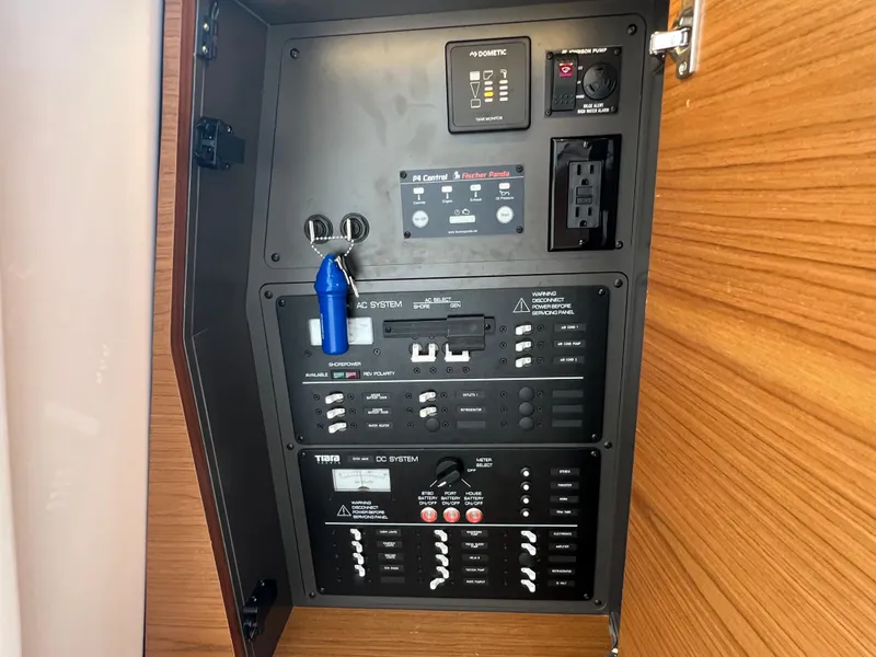 Slide: The Image of Electrical panel inside 2022 Tiara Yachts 34 LX, featuring AC and DC system controls. - 49