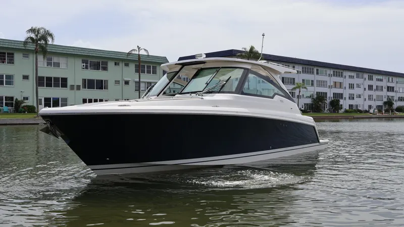 Slide: The Image of 2022 Tiara Yachts 34 LX cruising on a calm waterway near residential buildings. - 7