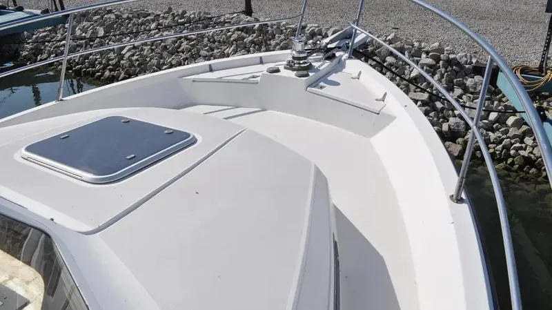 Slide: The Image of 1998 Sabre 36 Fast Trawler bow with railing and hatch, docked by rocky shore. - 3