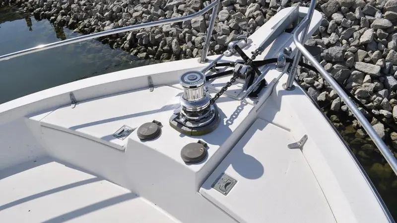 Slide: The Image of Bow of 1998 Sabre 36 Fast Trawler with winch and railings, docked by rocky shore. - 8