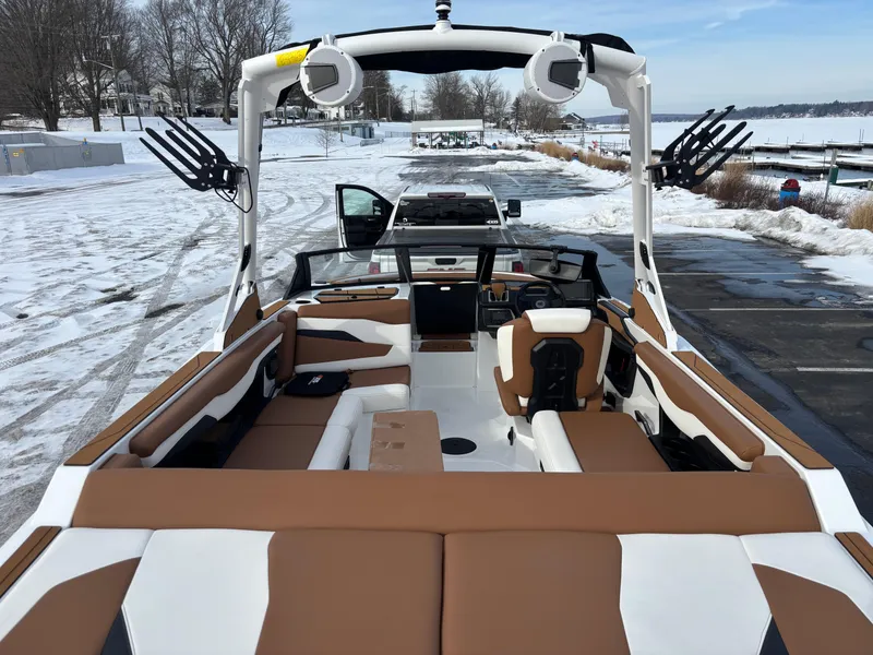 Slide: The Image of 2025 Axis T220 boat with brown and white interior, parked on snowy lakeside. - 11