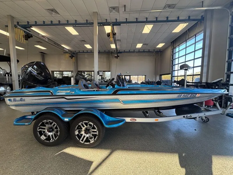 Slide: The Image of 2020 Bass Cat Puma FTD boat in showroom, blue and white design, on a trailer. - 5