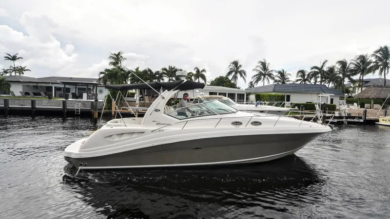 Slide: The Image of 2007 Sea Ray 340 Sundancer yacht cruising on a calm waterway with palm trees in the background. - 0