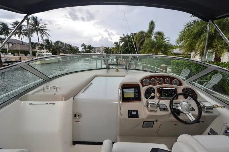 Slide: The Image of 2007 Sea Ray 340 Sundancer helm with modern controls, docked near palm trees and waterfront homes. - 11