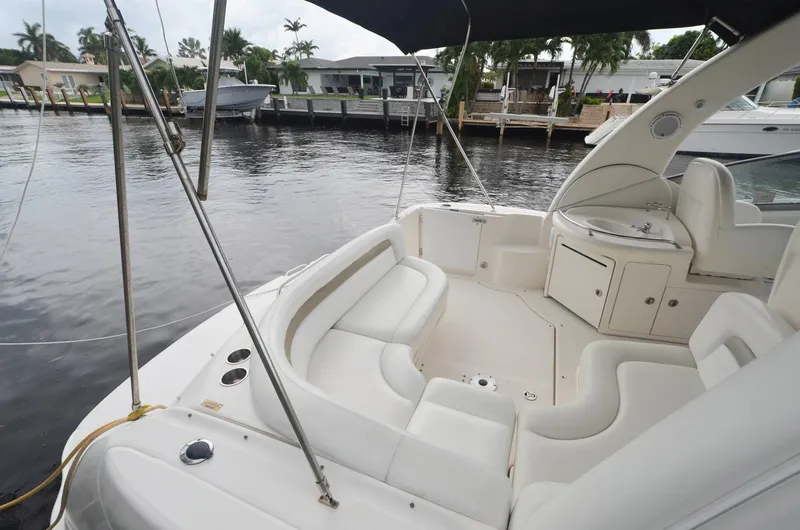 Slide: The Image of 2007 Sea Ray 340 Sundancer boat interior with white seating, docked by waterfront homes. - 28