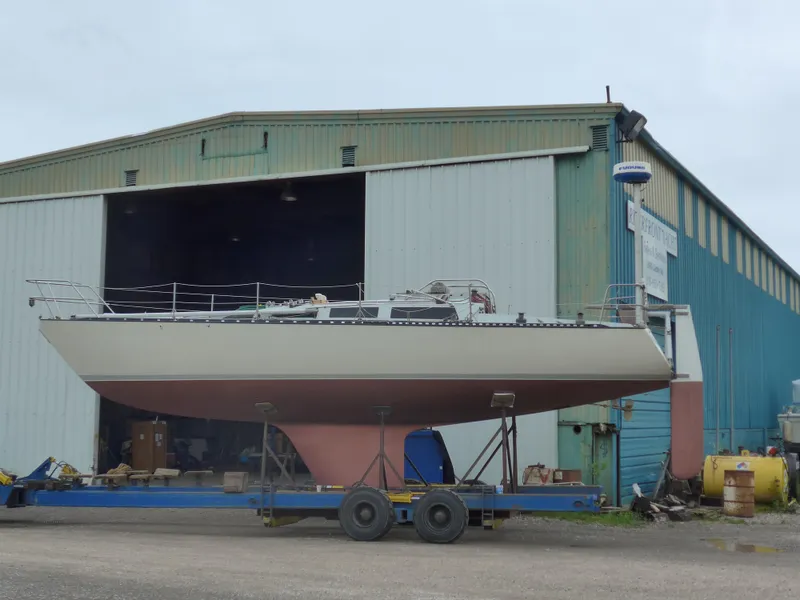 Slide: The Image of Sailboat on trailer outside a large industrial building, Abbott 36 model, 1986. - 2