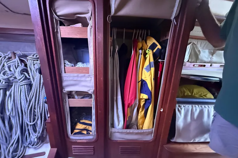 Slide: The Image of Sailboat interior with storage, ropes, and hanging jackets on an Abbott 36, 1986 model. - 37