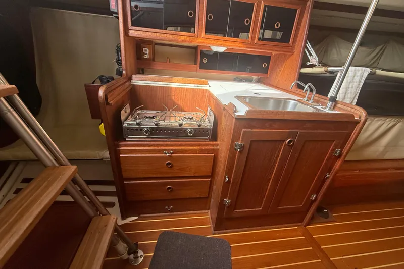 Slide: The Image of 1986 Abbott 36 yacht interior with wooden cabinetry, stove, and sink in compact kitchen area. - 44