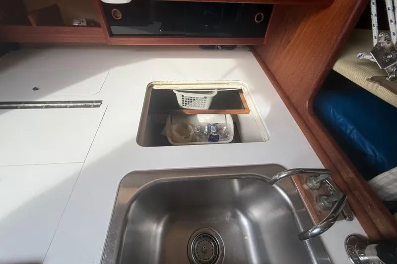 Slide: The Image of Kitchen sink area in a 1986 Abbott 36 sailboat, featuring a stainless steel sink and storage compartment. - 46