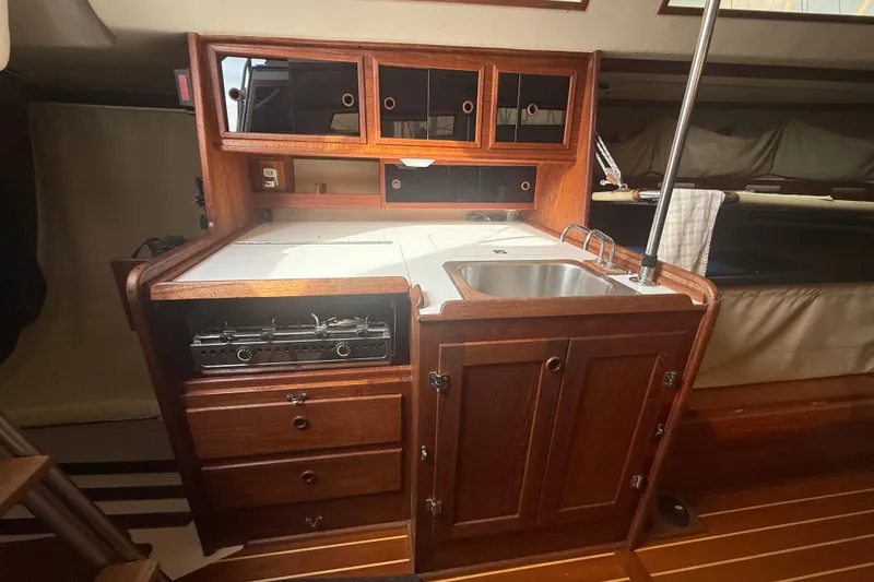 Slide: The Image of Wooden yacht galley with sink, stove, and storage cabinets. Abbott 36, 1986 model. - 48