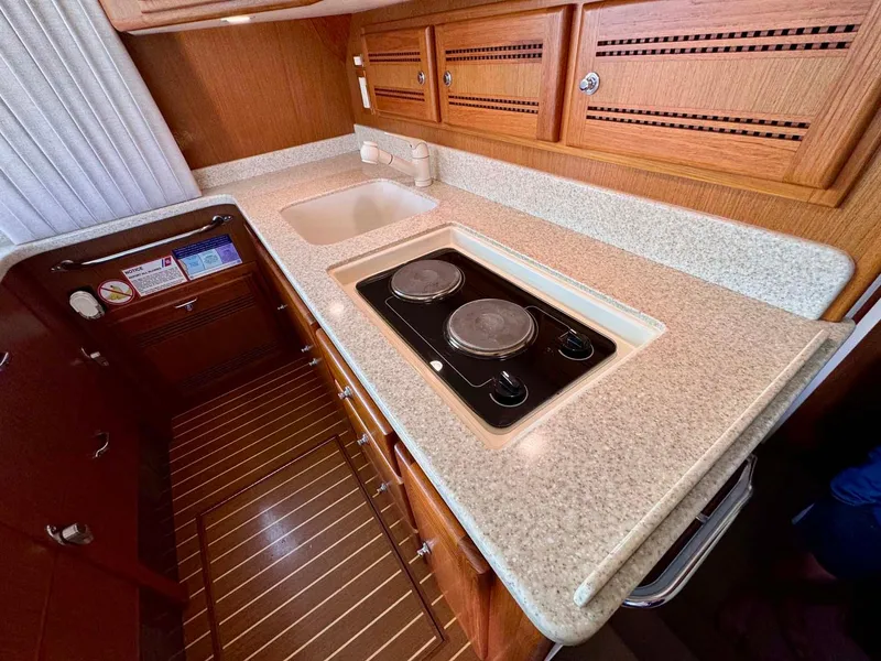 Slide: The Image of 2002 Cabo 47 Flybridge Sportfisher kitchen with stove, sink, and wooden cabinets. - 12