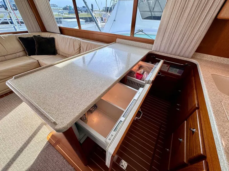 Slide: The Image of Interior of 2002 Cabo 47 Flybridge Sportfisher with open kitchen drawers and beige seating. - 13