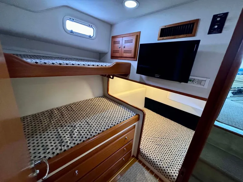 Slide: The Image of 2002 Cabo 47 Flybridge Sportfisher cabin with bunk beds and TV. - 16