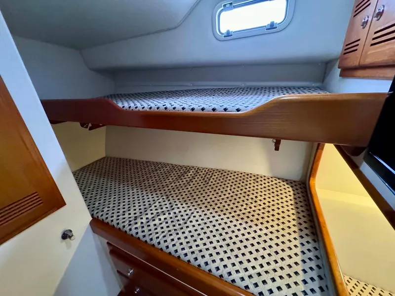 Slide: The Image of Bunk beds in 2002 Cabo 47 Flybridge Sportfisher cabin with wooden accents and window. - 17