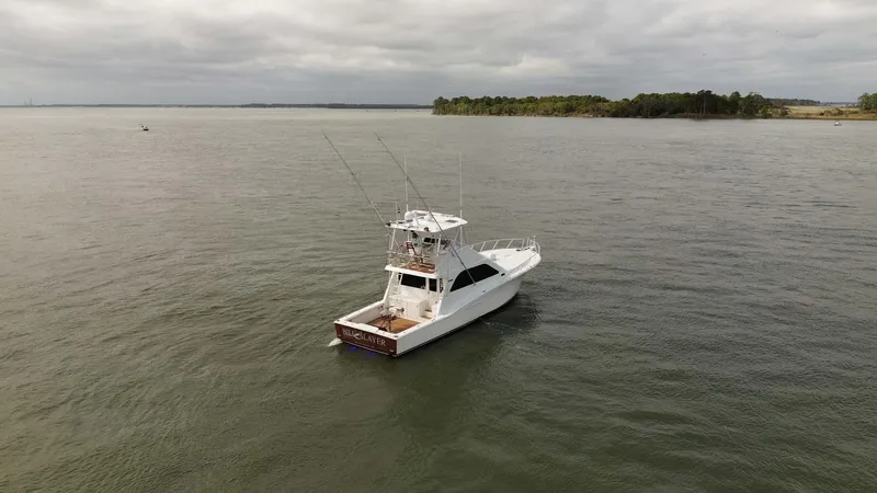 Slide: The Image of 2002 Cabo 47 Flybridge Sportfisher on calm waters under cloudy skies. - 2