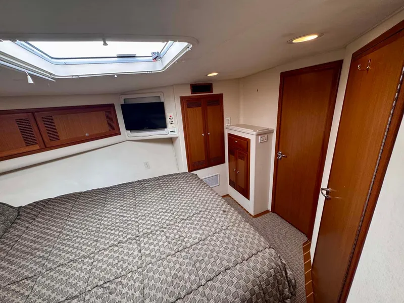 Slide: The Image of 2002 Cabo 47 Flybridge Sportfisher cabin interior with bed, TV, and wooden cabinetry. - 22
