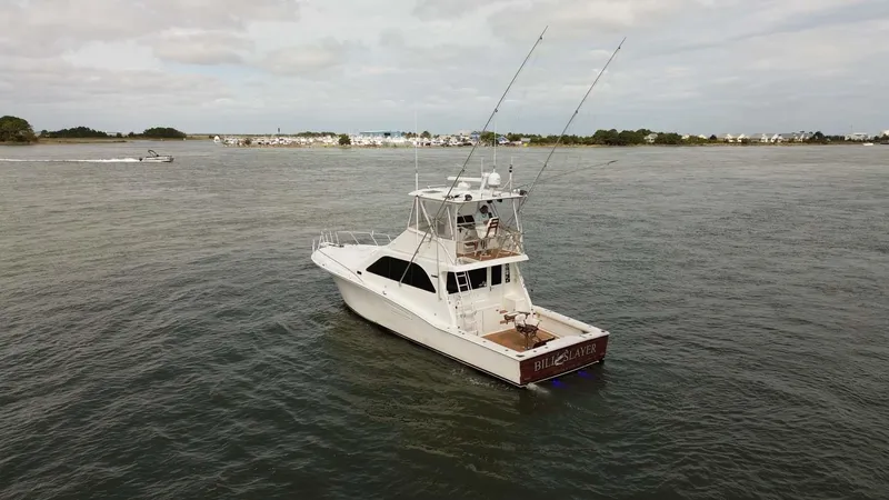 Slide: The Image of 2002 Cabo 47 Flybridge Sportfisher on calm waters, distant shoreline in background. - 3