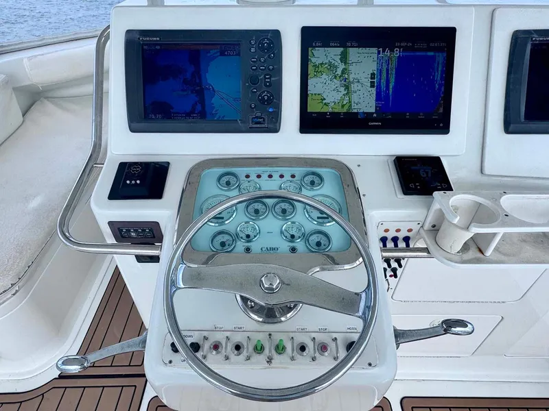 Slide: The Image of 2002 Cabo 47 Flybridge Sportfisher helm with navigation screens and controls. - 38