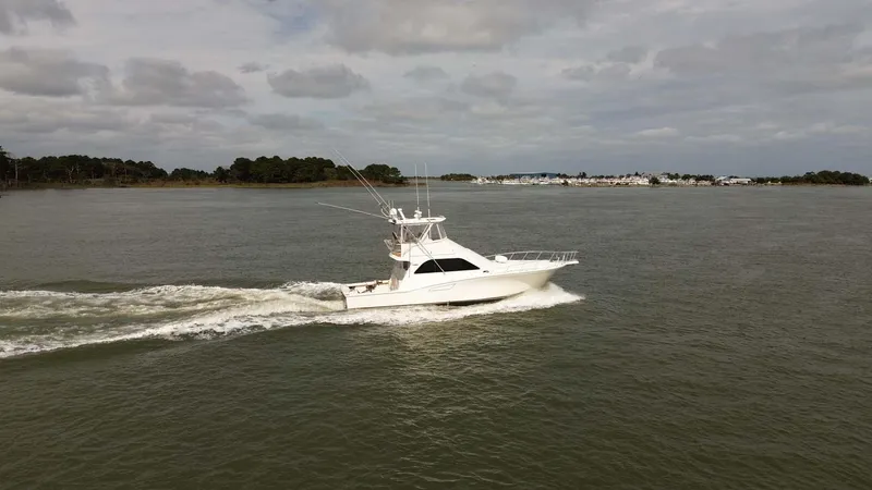 Slide: The Image of 2002 Cabo 47 Flybridge Sportfisher cruising on open water under cloudy skies. - 7