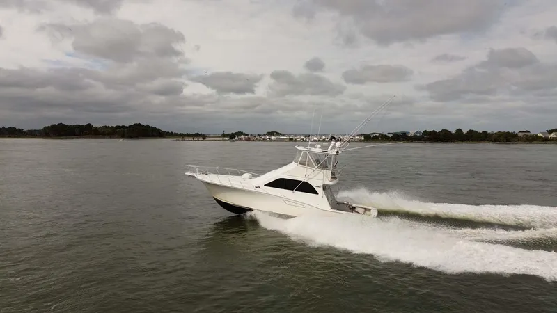 Slide: The Image of 2002 Cabo 47 Flybridge Sportfisher cruising on open water under cloudy skies. - 8