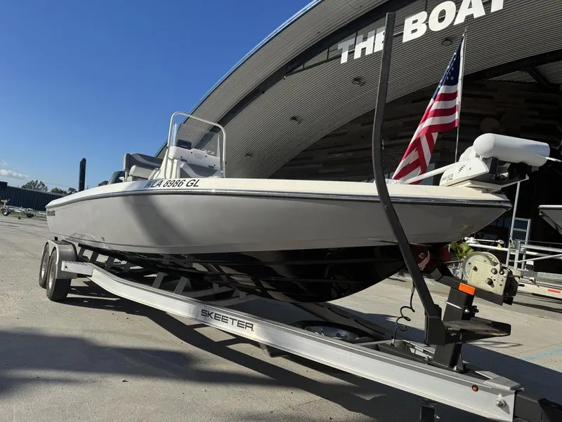 Slide: The Image of 2019 Skeeter SX 240 boat on trailer with American flag, parked outside a building. - 4