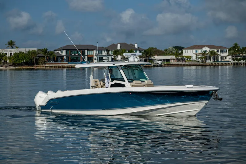 The Image of 2024 Boston Whaler 380 Outrage boat on calm water, with waterfront homes in the background. - 1