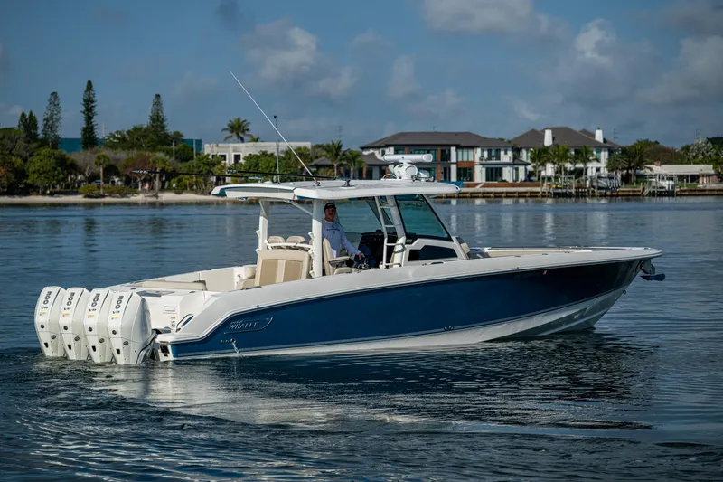 Slide: The Image of 2024 Boston Whaler 380 Outrage boat cruising on calm waters near a coastal residence. - 18
