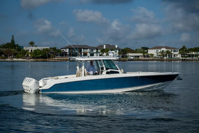 Slide: The Image of 2024 Boston Whaler 380 Outrage cruising on calm waters near waterfront homes. - 20