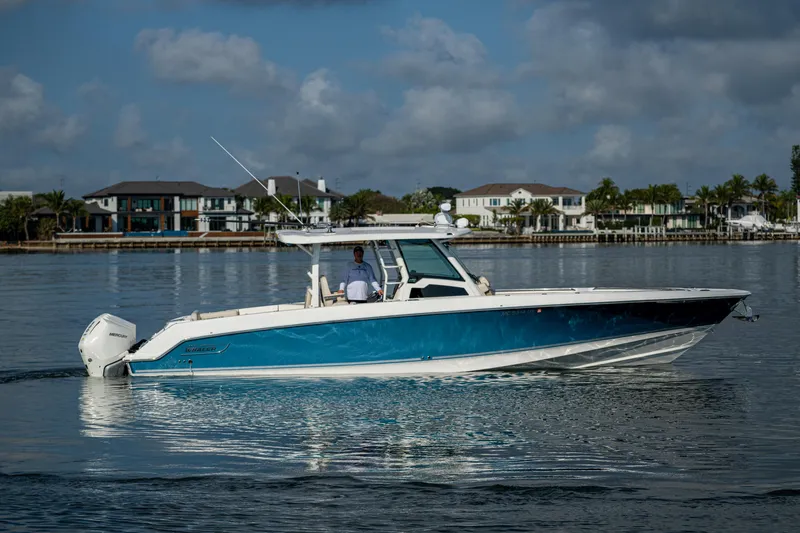 Slide: The Image of 2024 Boston Whaler 380 Outrage cruising on calm waters near waterfront homes. - 21