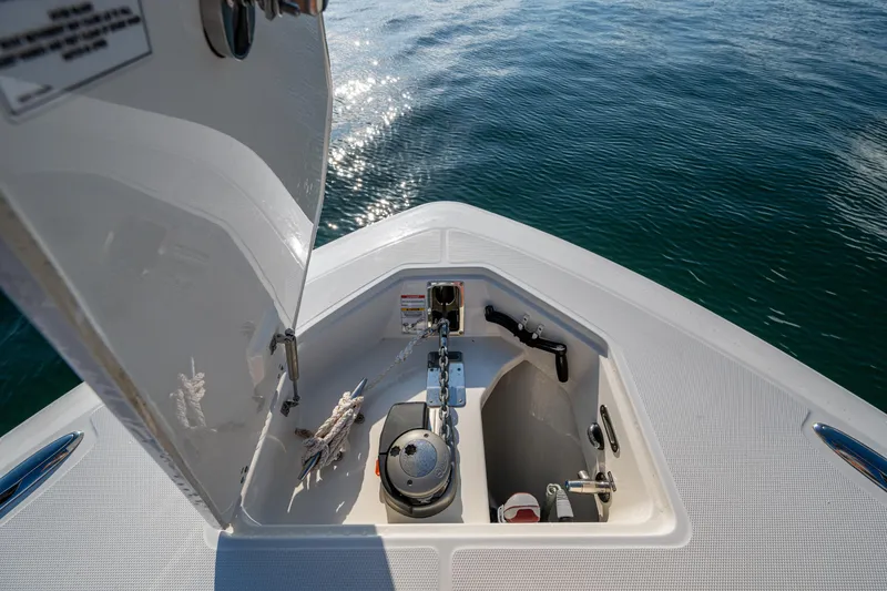 Slide: The Image of 2024 Boston Whaler 380 Outrage anchor compartment with open hatch, on calm water. - 27
