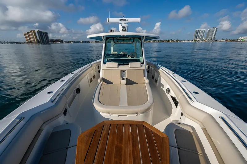 Slide: The Image of 2024 Boston Whaler 380 Outrage boat on calm water, featuring spacious deck and seating. - 29