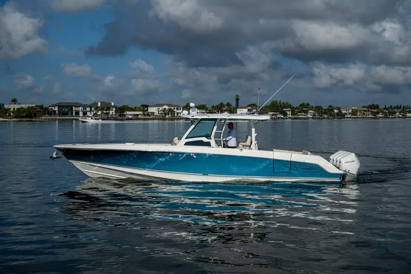 Slide: The Image of 2024 Boston Whaler 380 Outrage boat cruising on calm waters under cloudy skies. - 8