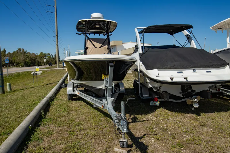 Slide: The Image of 2021 Pioneer 202 Islander boat on trailer, parked outdoors under clear blue sky. - 21