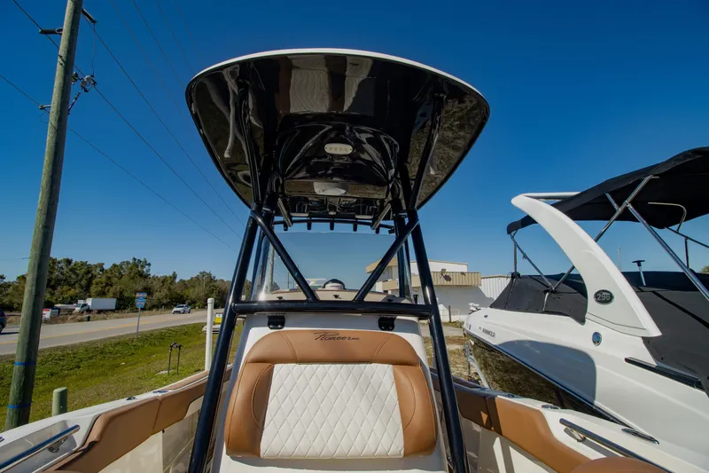 Slide: The Image of 2021 Pioneer 202 Islander boat with T-top and cushioned seating, parked outdoors. - 8