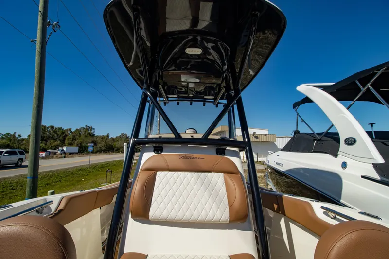 Slide: The Image of 2021 Pioneer 202 Islander boat interior with tan and white seating under a clear blue sky. - 9