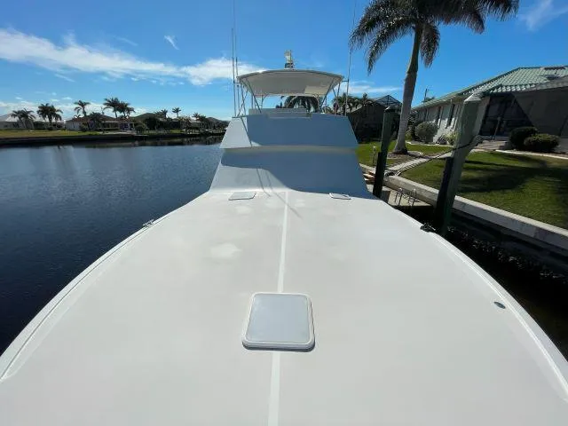 Slide: The Image of 1999 Viking 50 Convertible yacht docked by palm trees and waterfront homes. - 13