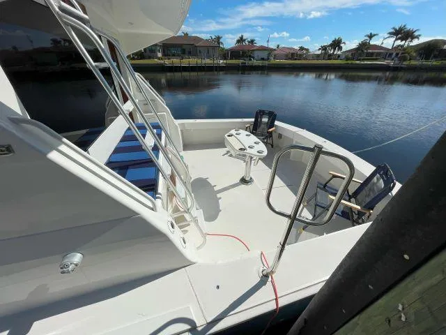 Slide: The Image of 1999 Viking 50 Convertible yacht docked by a serene waterfront. - 3